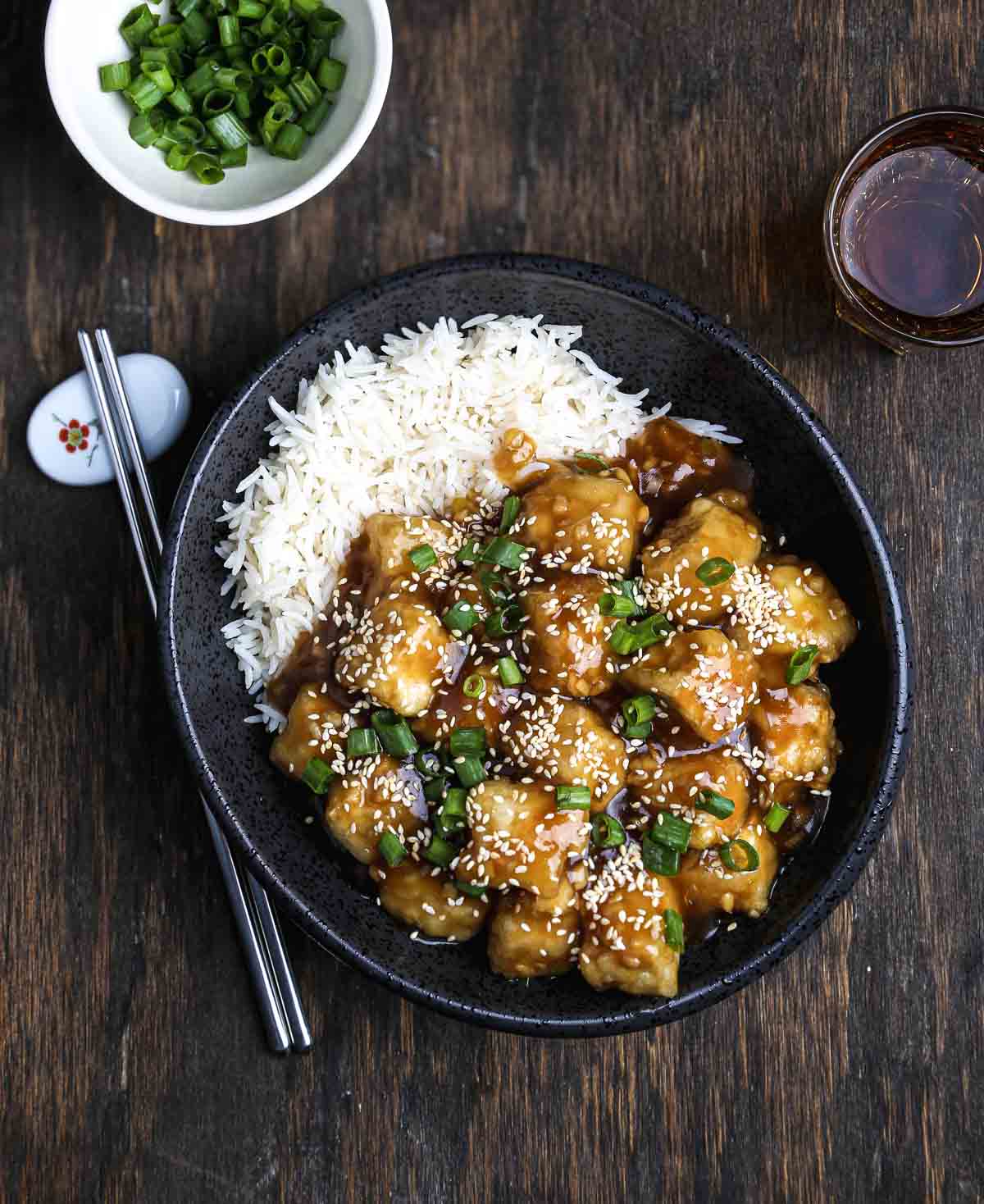 Close-up of General Tso's tofu coated in sticky glaze and sesame seeds.