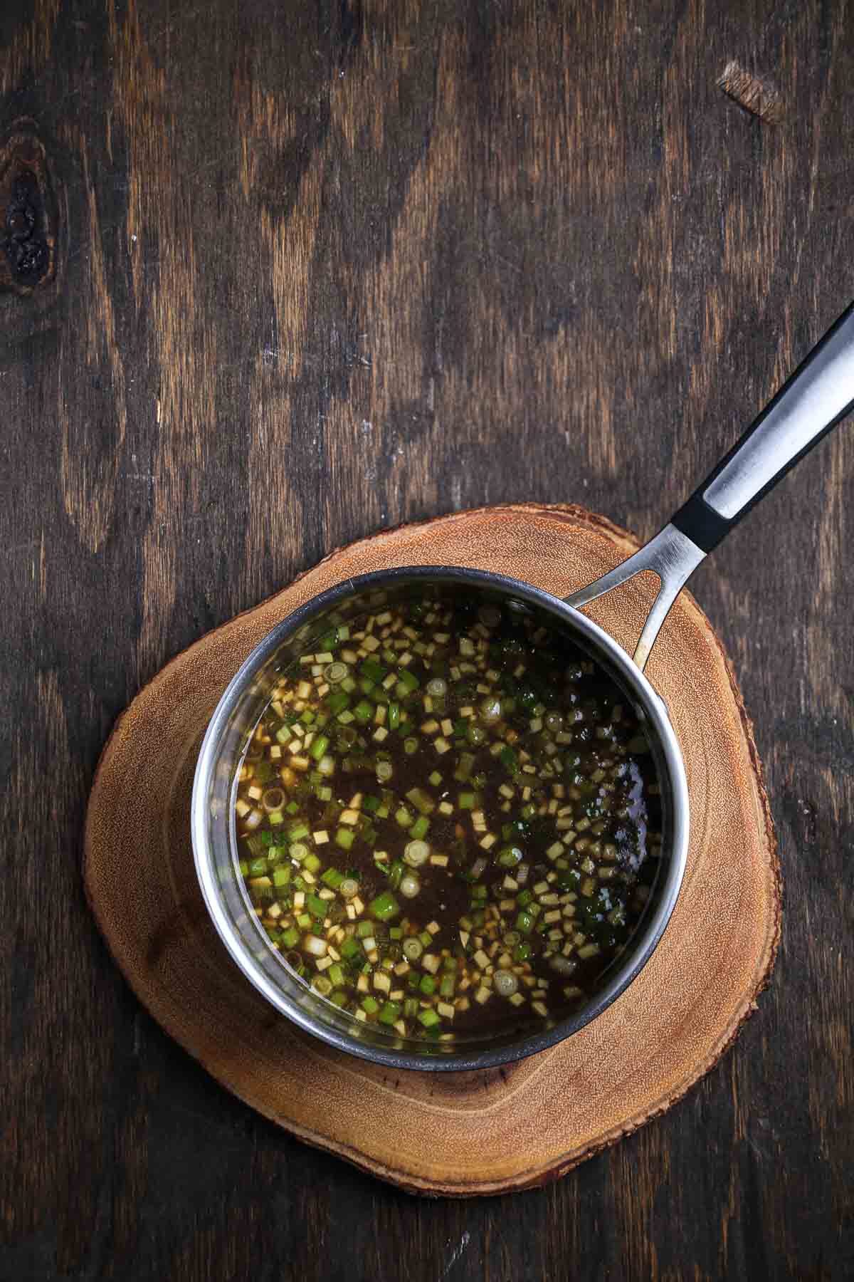 Sauce base with scallions, ginger, and garlic simmering in a saucepan.