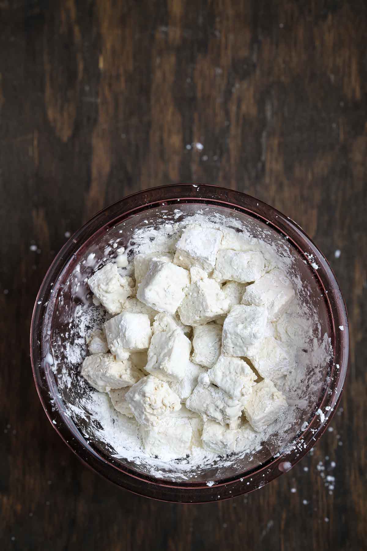 Tofu cubes fully dredged in cornstarch, prepared for frying.