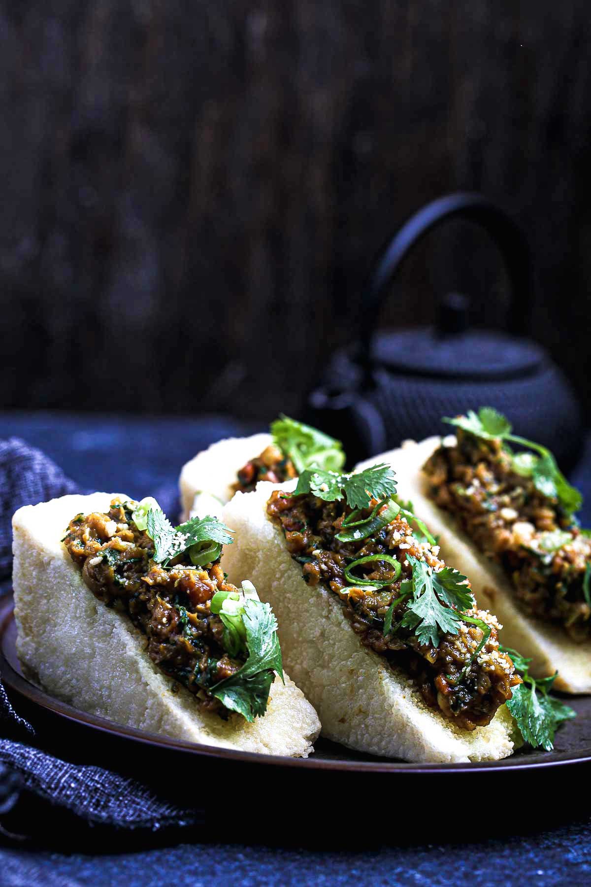 Golden fried tofu triangles filled with lemongrass-peanut sauce, topped with cilantro and scallions on a dark ceramic plate.