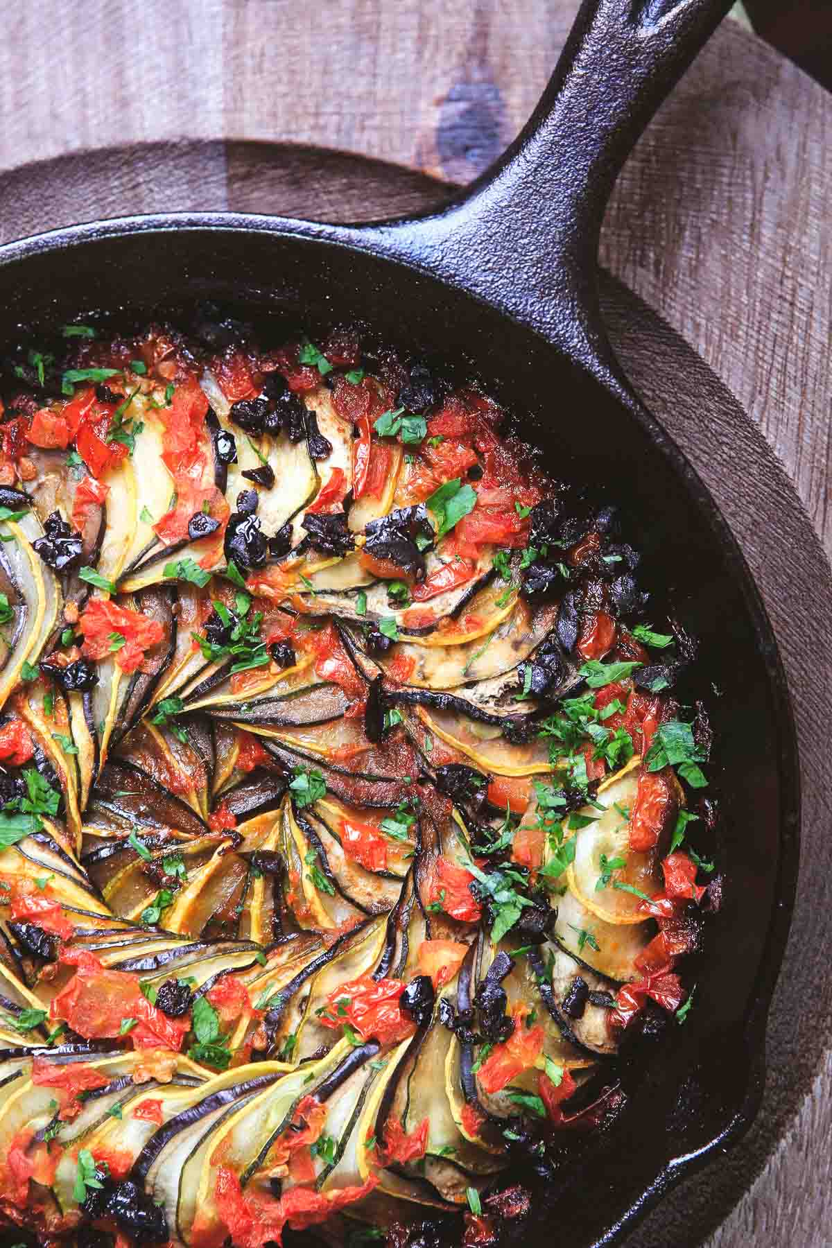 Baked ratatouille arranged in a spiral pattern with thin-sliced vegetables and tomato base.