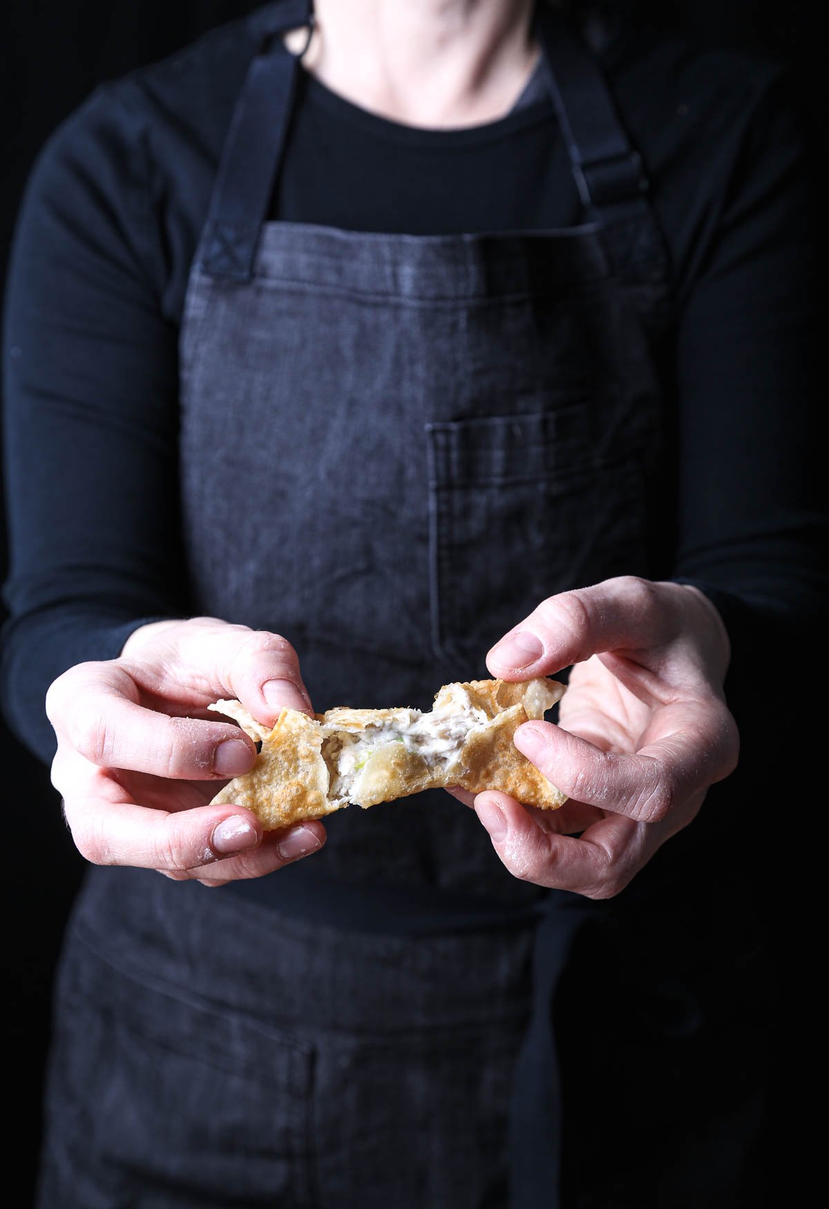 A vegan crab rangoon being torn apart to show its interior.