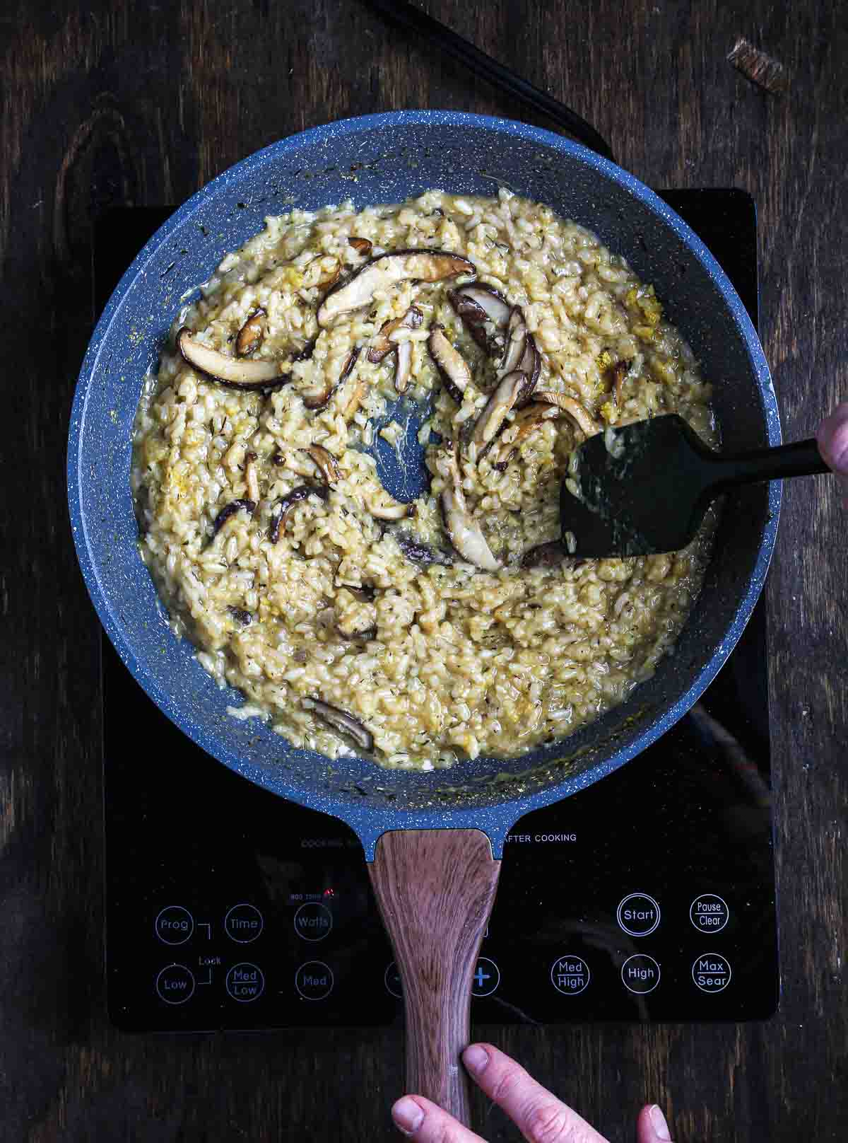 Seared shiitake mushrooms being folded into creamy vegan mushroom risotto.