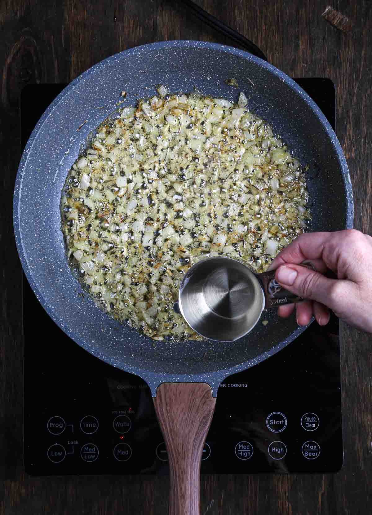 White wine being added to deglaze the pan while making vegan mushroom risotto.