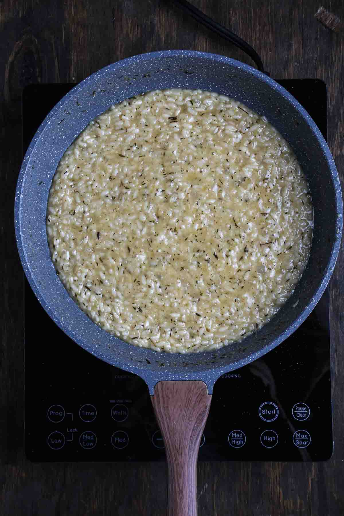Creamy vegan mushroom risotto showing glossy texture as the rice finishes cooking.