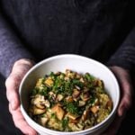 Vegan mushroom risotto topped with seared shiitakes and fresh herbs, served in a white bowl.