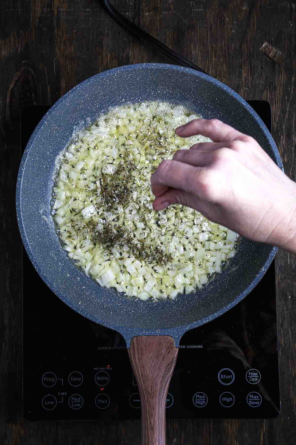 Dried thyme added to sautéed onions to build flavor for mushroom risotto.