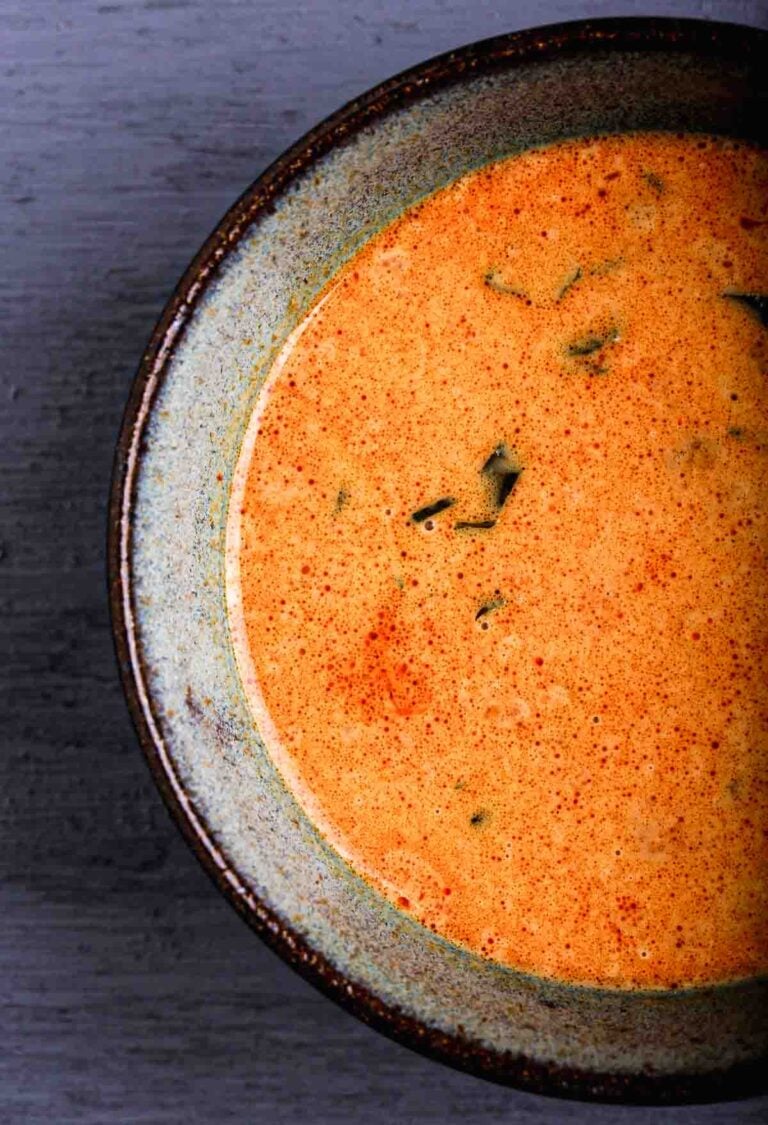 A bowl of vegan red curry sauce made with coconut milk, ginger, and basil.