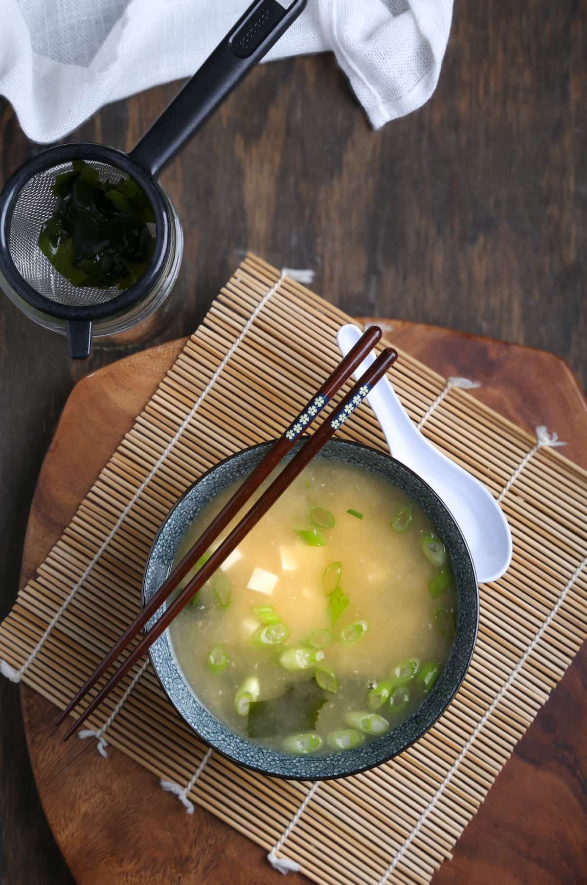 A bowl of vegan miso soup served on a bamboo mat.