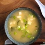 A bowl of vegan miso soup with seaweed and scallions.