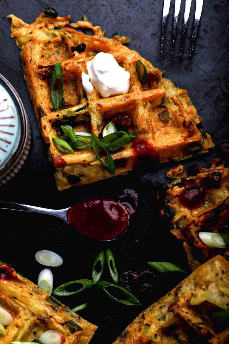 Crispy loaded hash brown waffles with melted vegan cheese, scallions, and sour cream.