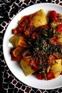 A plate of ravioli with creamy pasta sauce and basil.