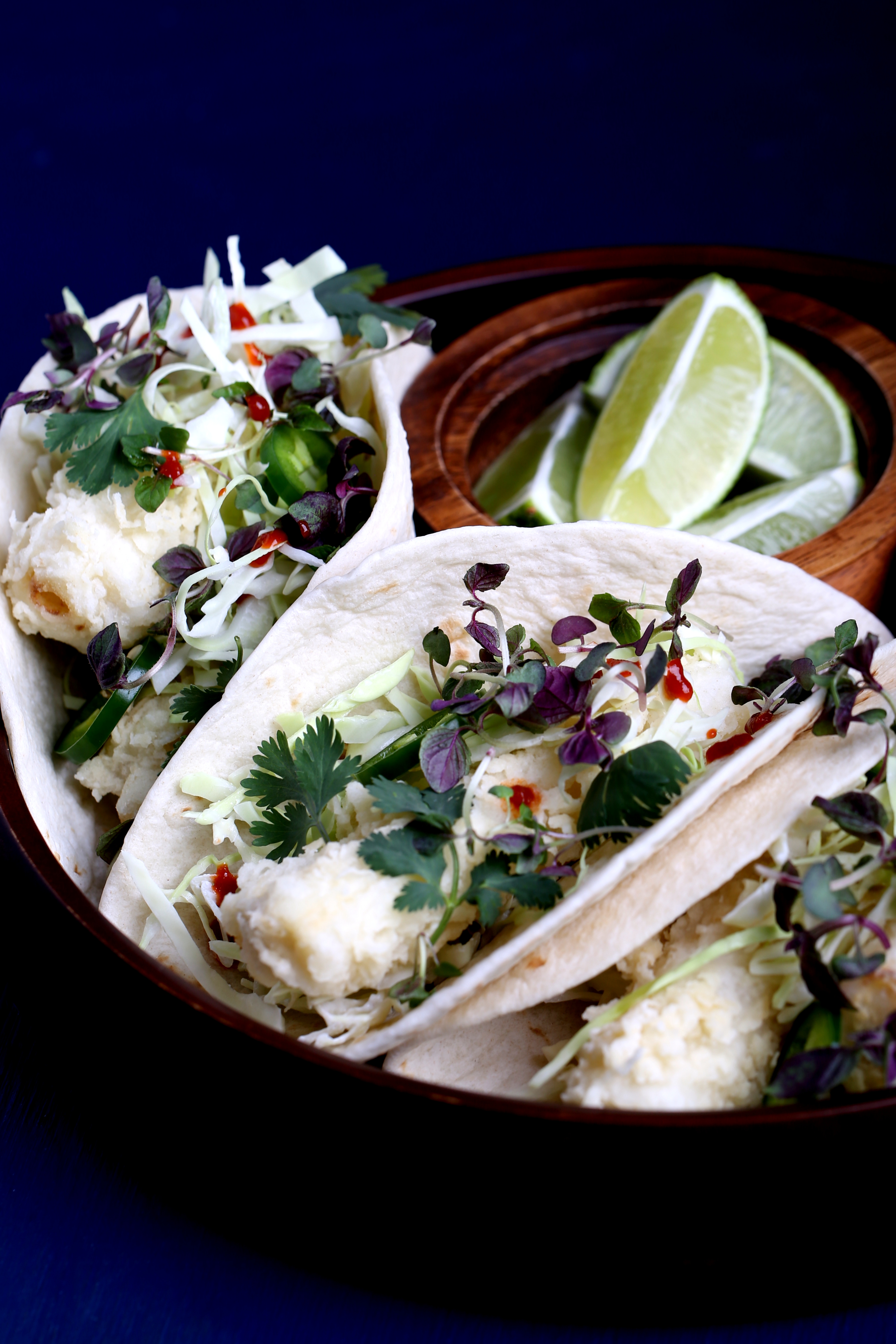 Hearts of palm tacos served in soft tortillas with cabbage, cilantro, and lime wedges.