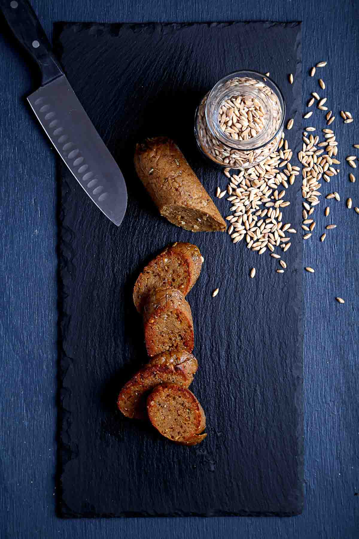Sliced vegan Italian sausage browned in a skillet, showing the coarse farro texture inside.