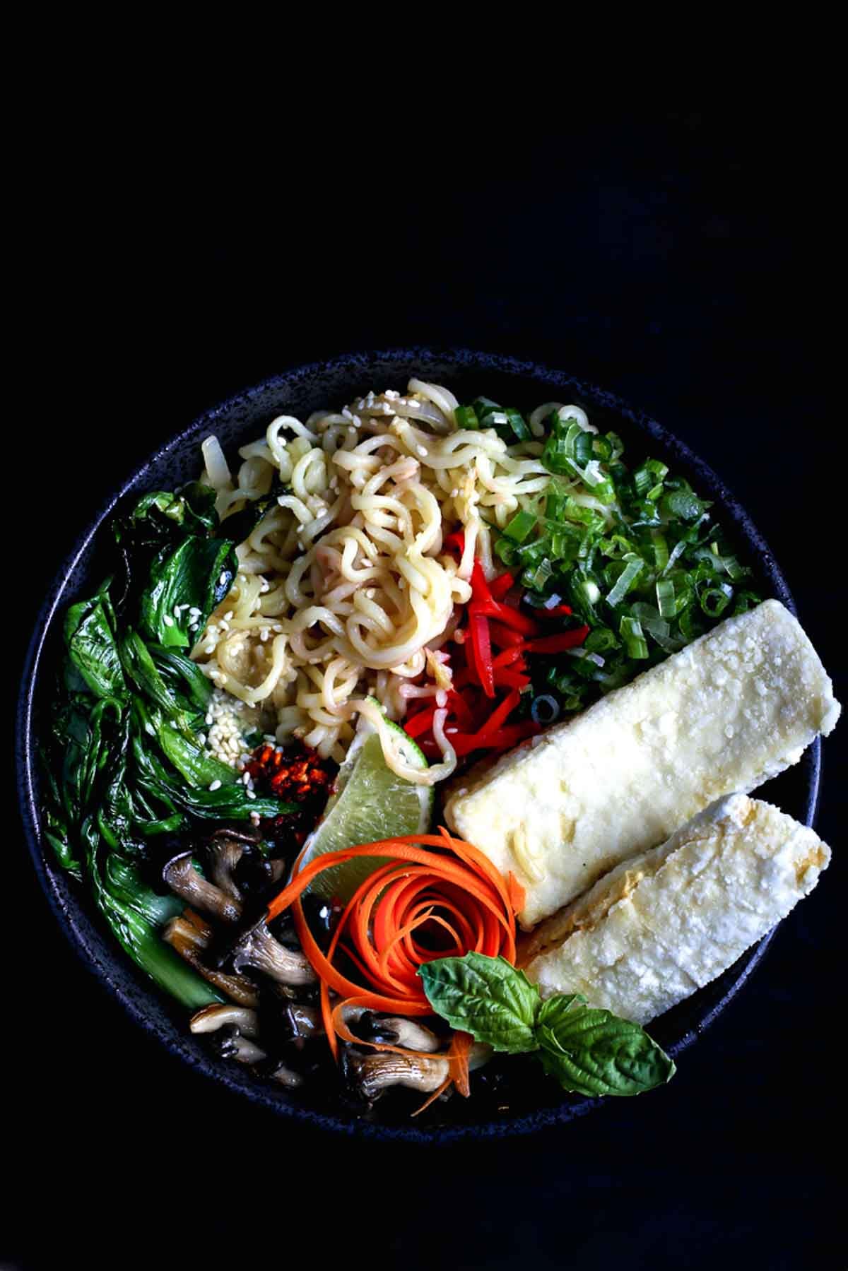 Bowl of vegan ramen with tofu, bok choy, mushrooms, and broth.