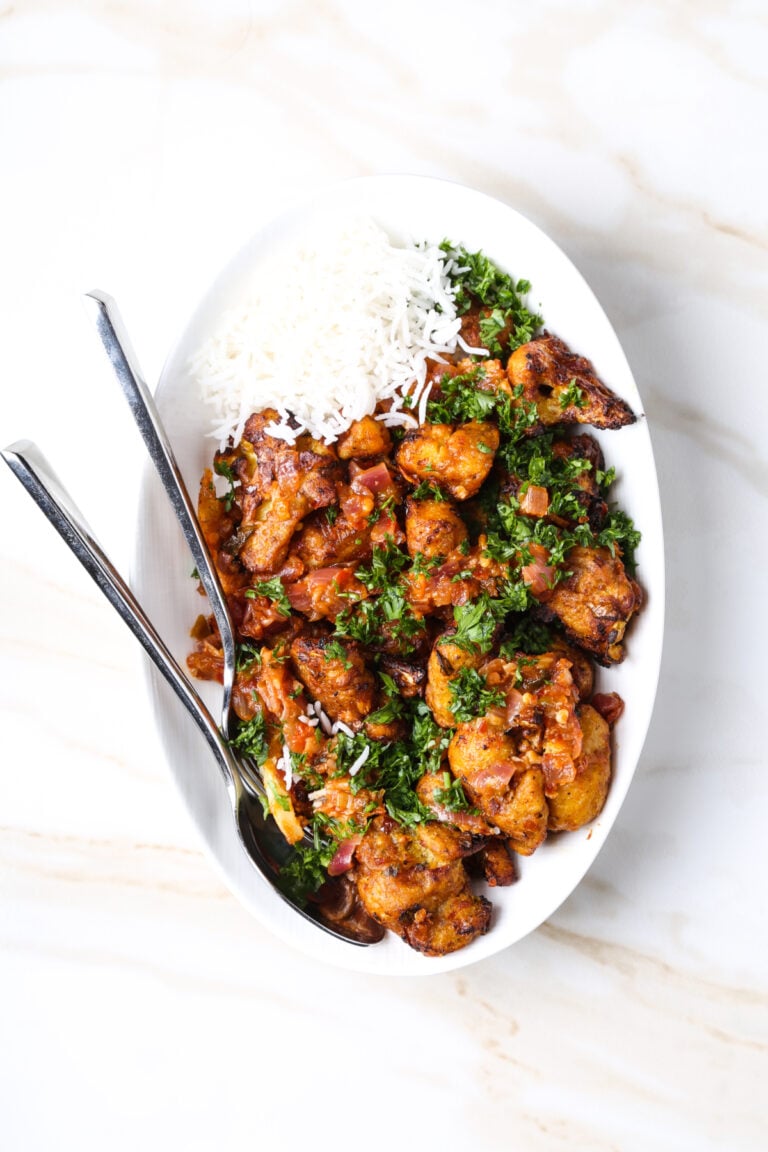A bowl Gobi Manchurian with rice and cilantro against a white background.