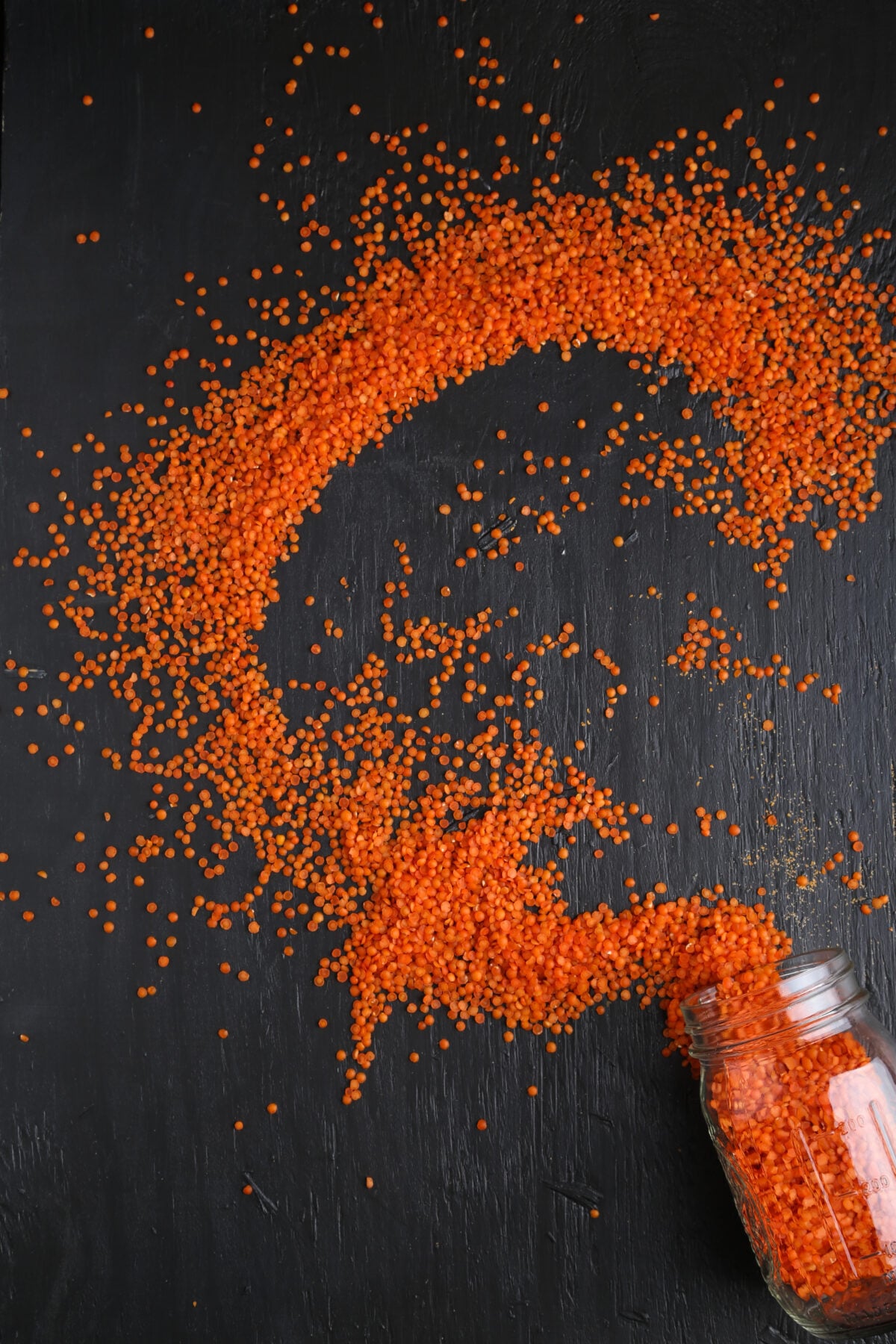 Red lentils spilled from a glass jar.