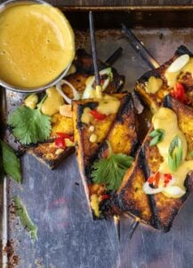 Satay tofu with peanut sauce on a tray.