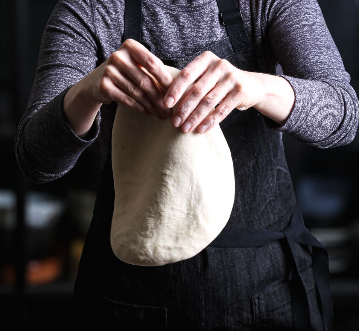 Stretching vegan pizza dough by hand into a round pizza crust.