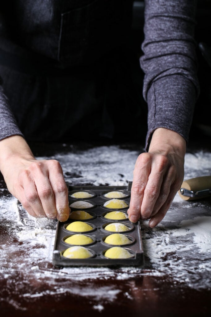 Lifting the ravioli mold to release the sealed ravioli.