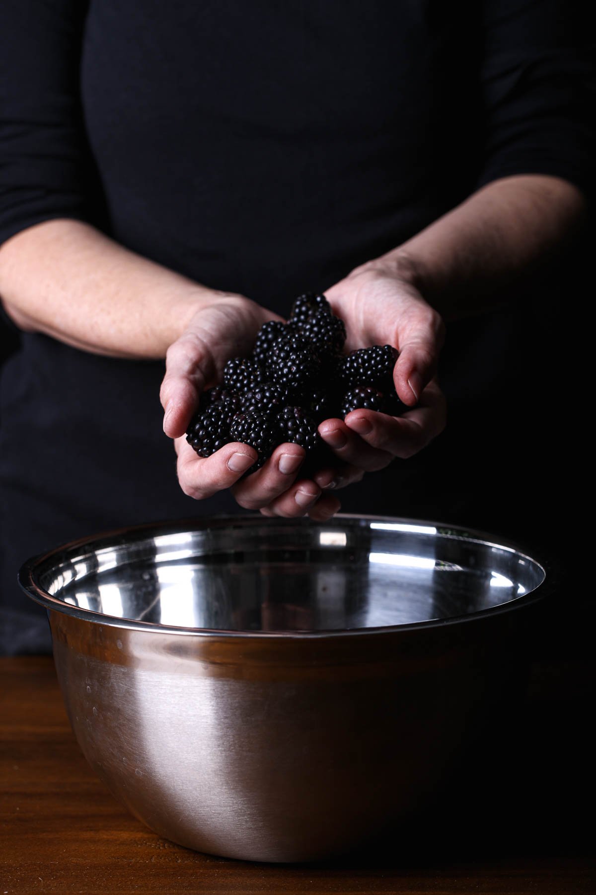 Blackberries gathered above a metal bowl, their deep color adding contrast to a mixed berry salad.