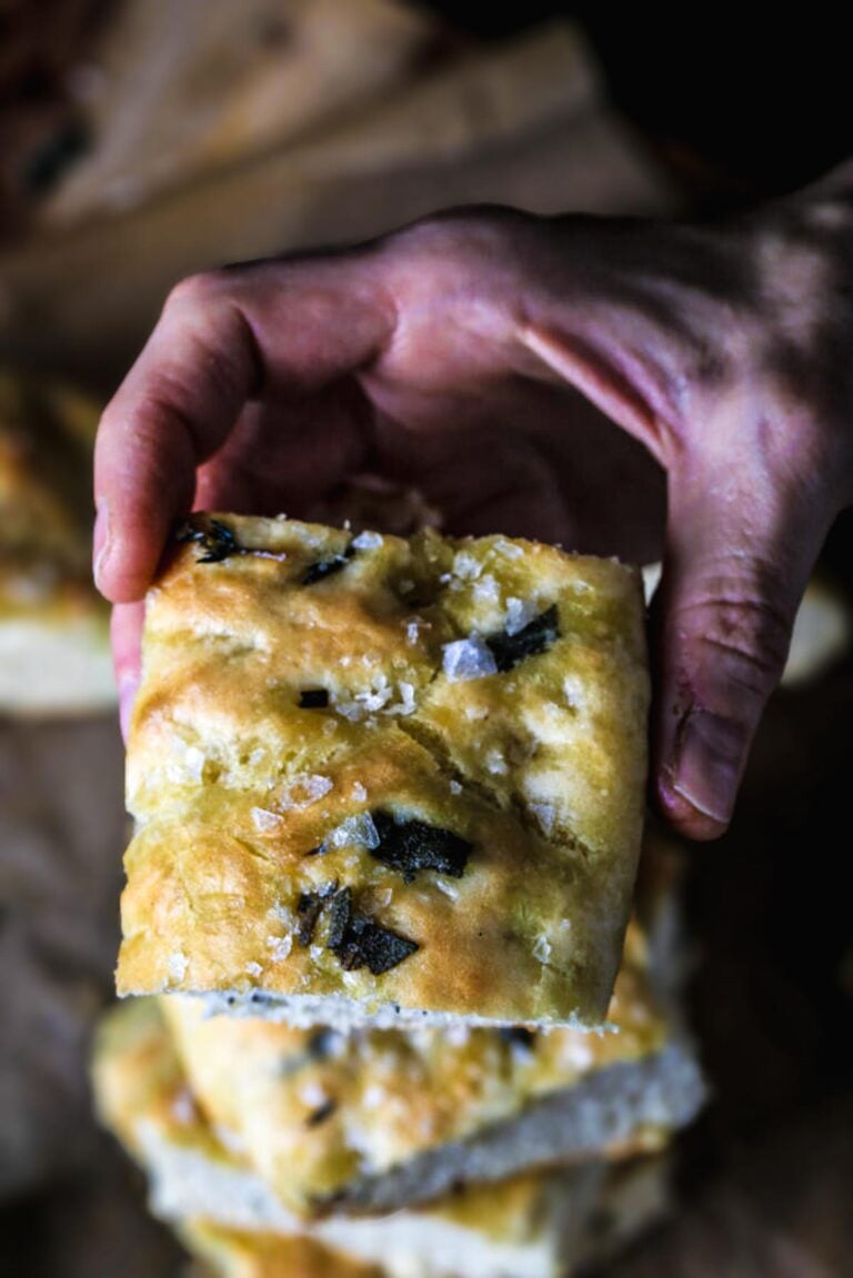 A hand holding a piece of quick and easy focaccia bread.