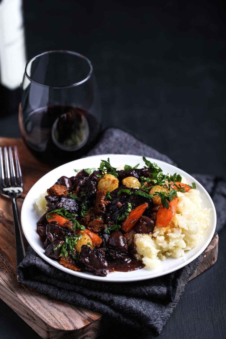 A glass of red wine beside a plate of vegan bourguignon, the ultimate slow-simmered plant-based stew for a comforting, elegant meal.