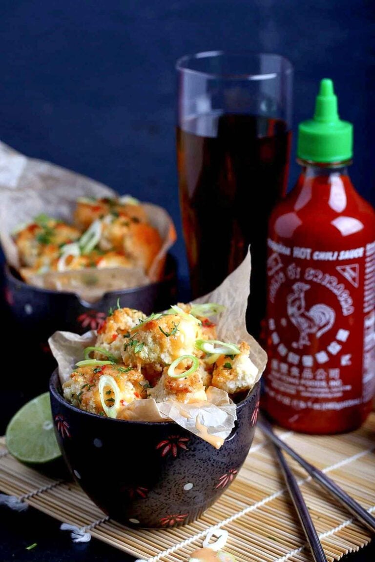 Crispy bang bang cauliflower coated in a creamy sweet-spicy sauce, topped with scallions.