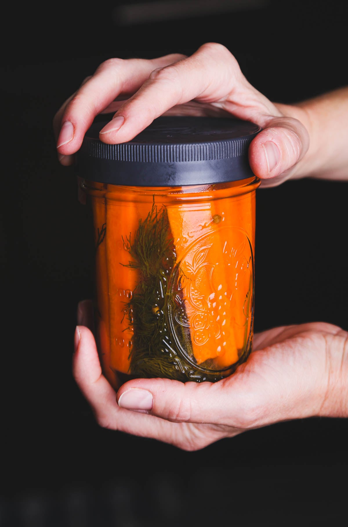 Pickled carrots in a glass jar with herbs, showing a simple way to extend their shelf life.