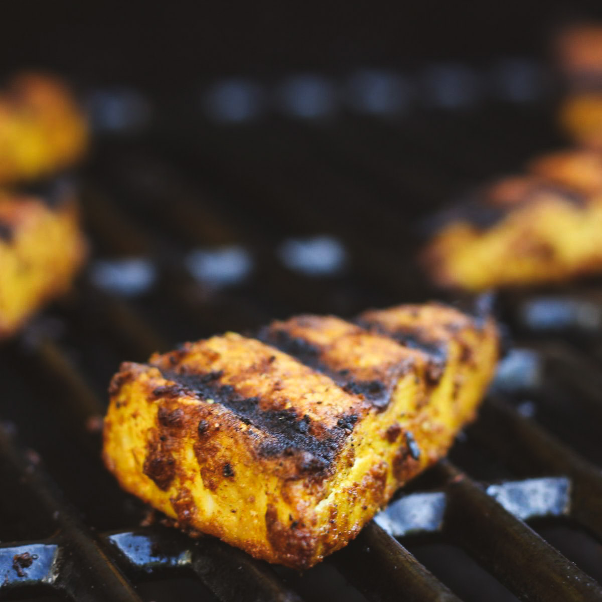 Grilled tofu slices with char marks on the grate.