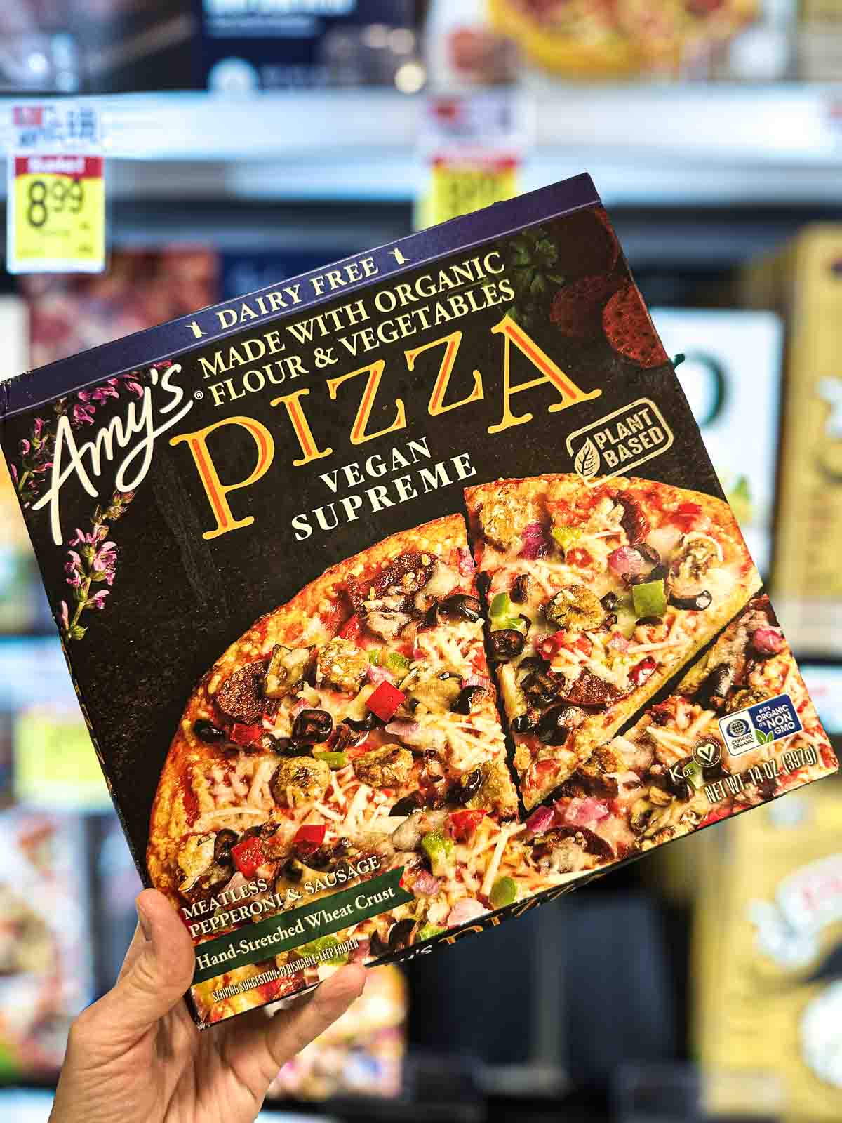 Amy’s Vegan Supreme Pizza package in freezer aisle with plant-based toppings and dairy-free cheese.