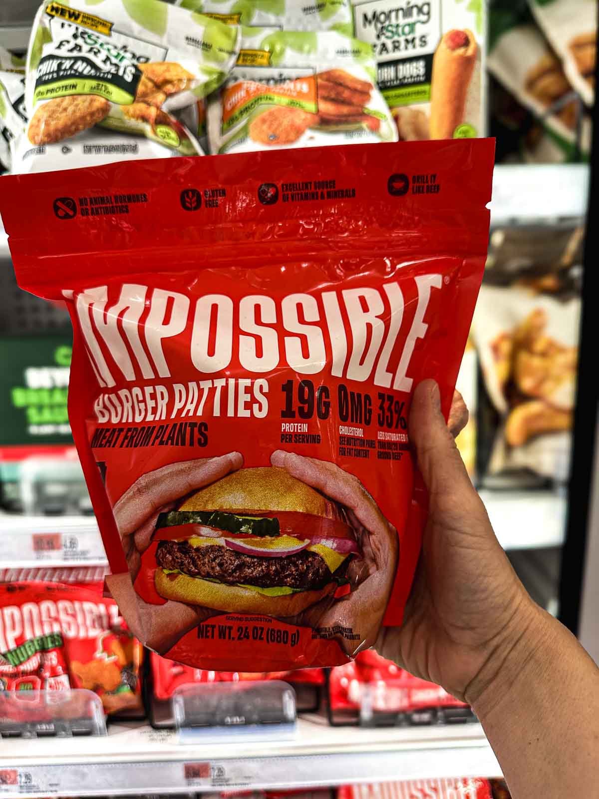 Impossible Burger frozen patties in red packaging with a close-up of a juicy vegan cheeseburger on the label.