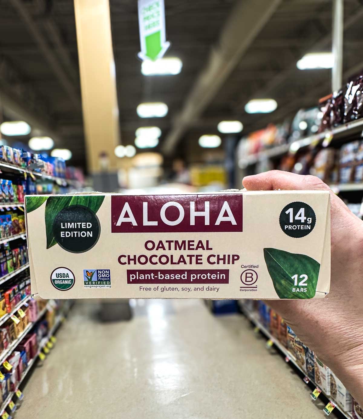 ALOHA oatmeal chocolate chip protein bars with 14g plant-based protein, shown in a grocery aisle.