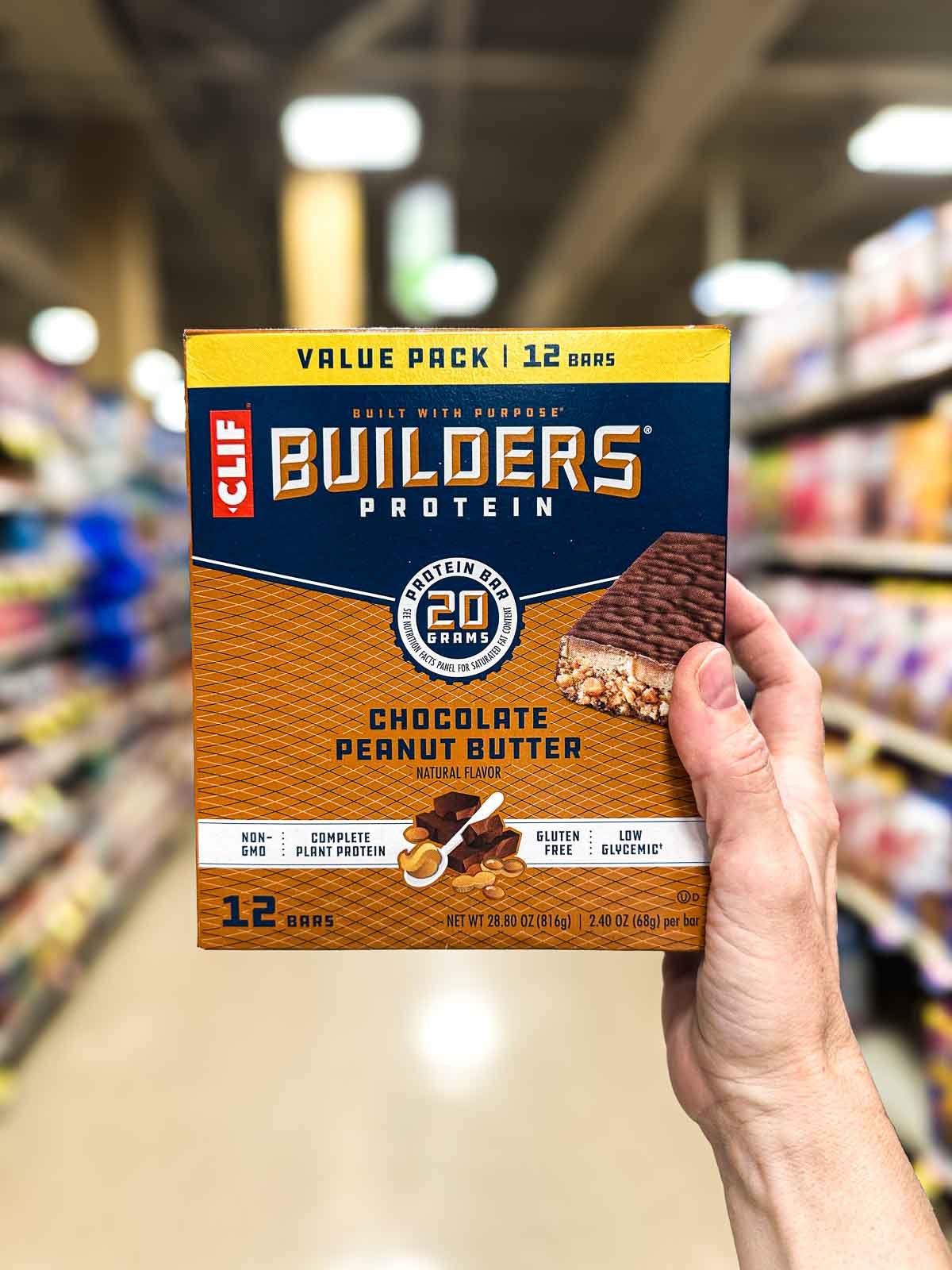Front of CLIF Builders vegan protein bars in a grocery store aisle, with navy and tan packaging with blocky lettering.