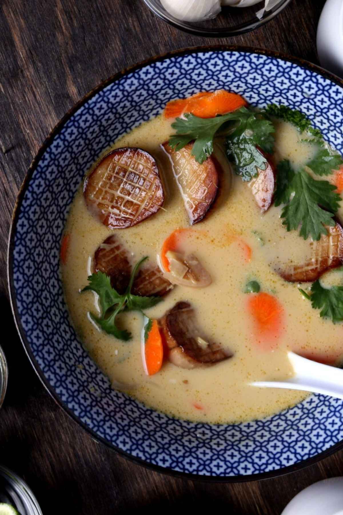 Vegan roasted ginger and coconut soup in a bowl with vegan scallops and fresh garnish.