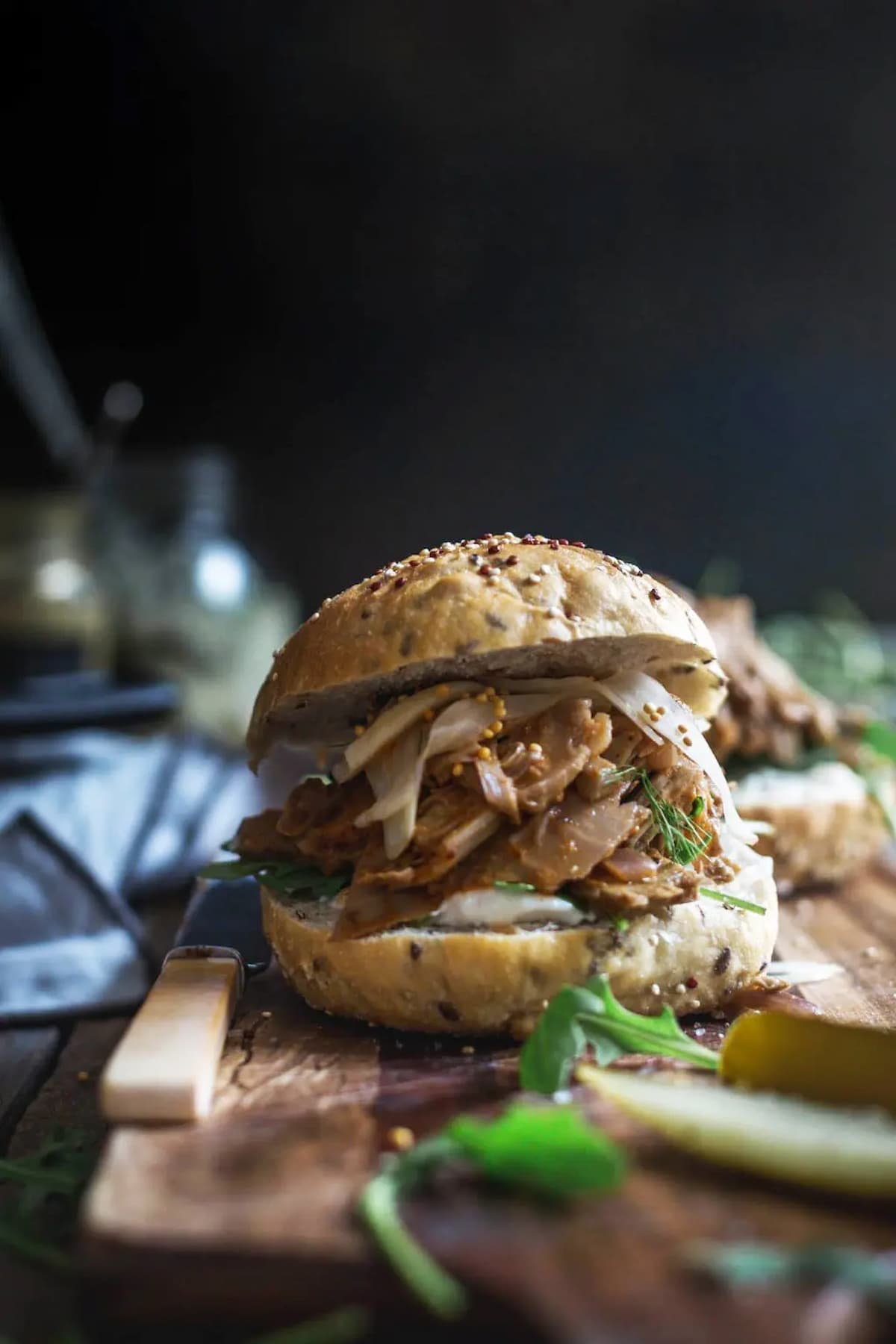 Creole-style jackfruit burger with smoky shredded jackfruit, mustard seeds, and greens on a seeded bun.
