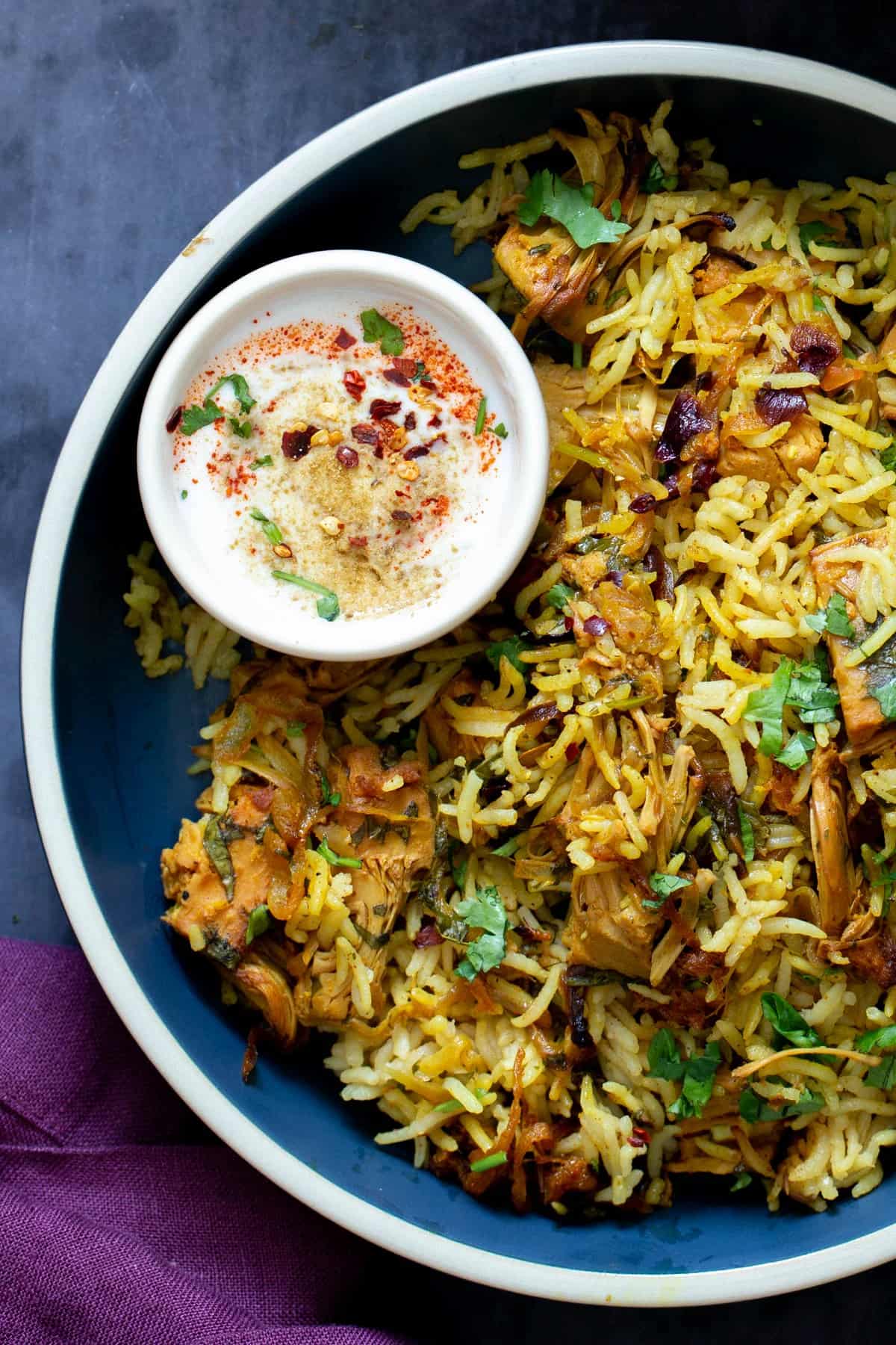 Baked jackfruit biryani with basmati rice, caramelized onions, and herbs served with spiced vegan yogurt sauce.