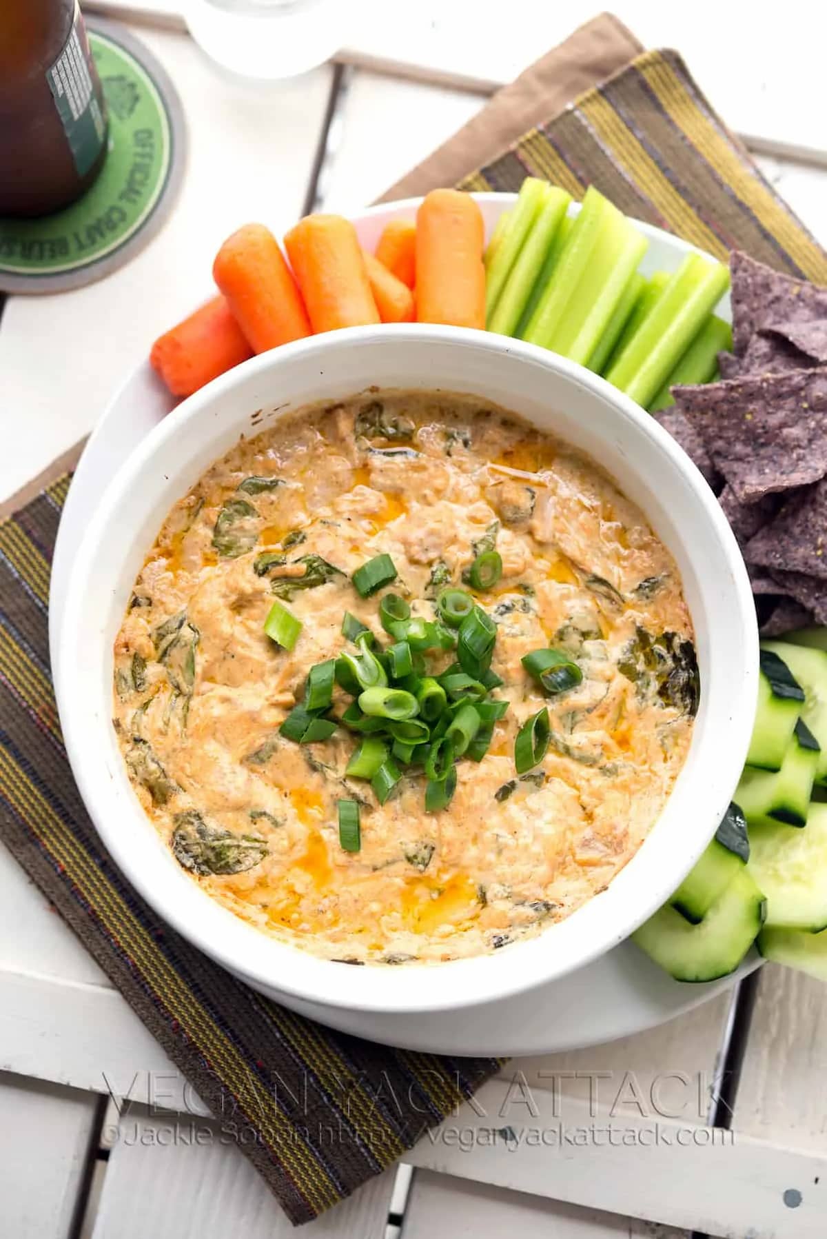Buffalo jackfruit dip baked until hot and bubbly, topped with green onions and served with carrots, celery, cucumbers, and tortilla chips.