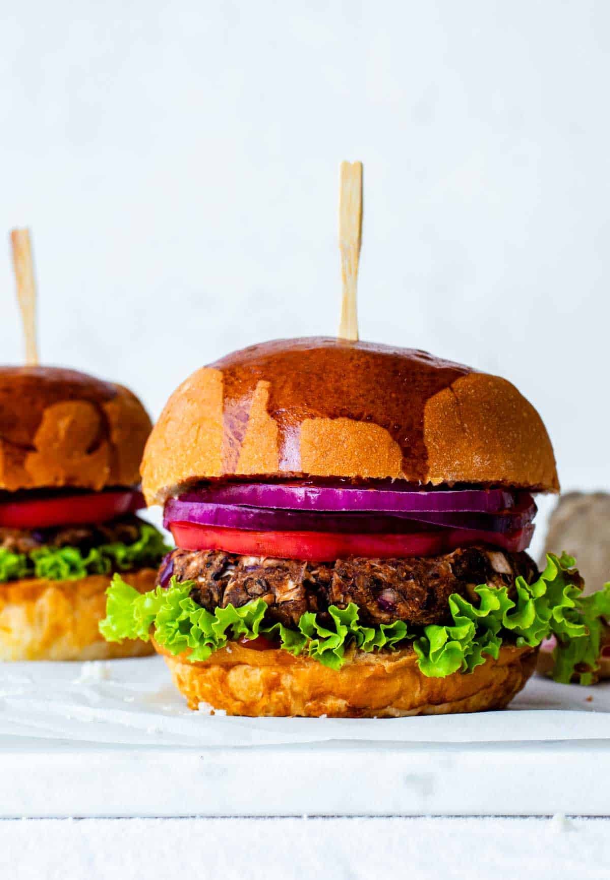 Vegan jackfruit burger patty stacked with lettuce, tomato, and red onion on a toasted bun.