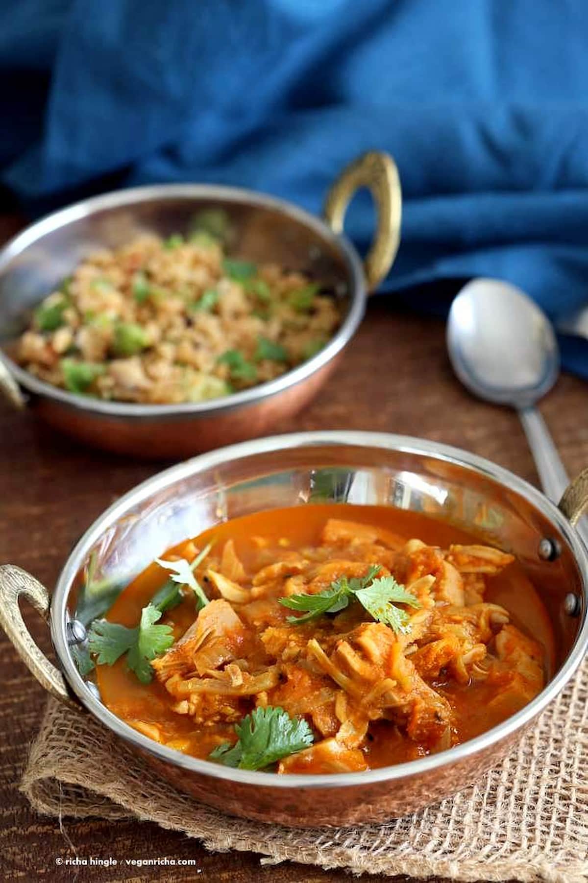 Vegan jackfruit curry simmered in spiced tomato sauce with cilantro, served with rice in a copper bowl.