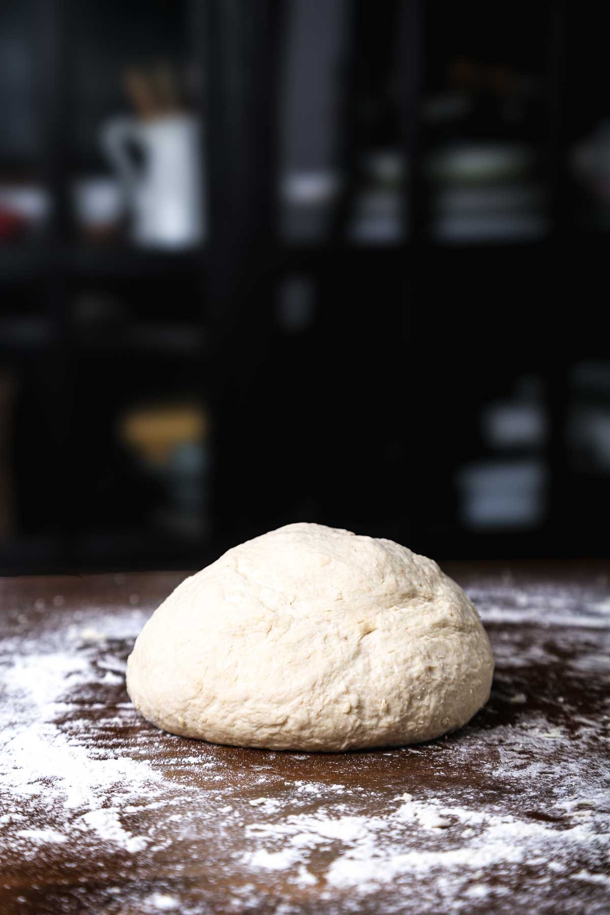 Soft, smooth ball of dough resting on a lightly floured surface.