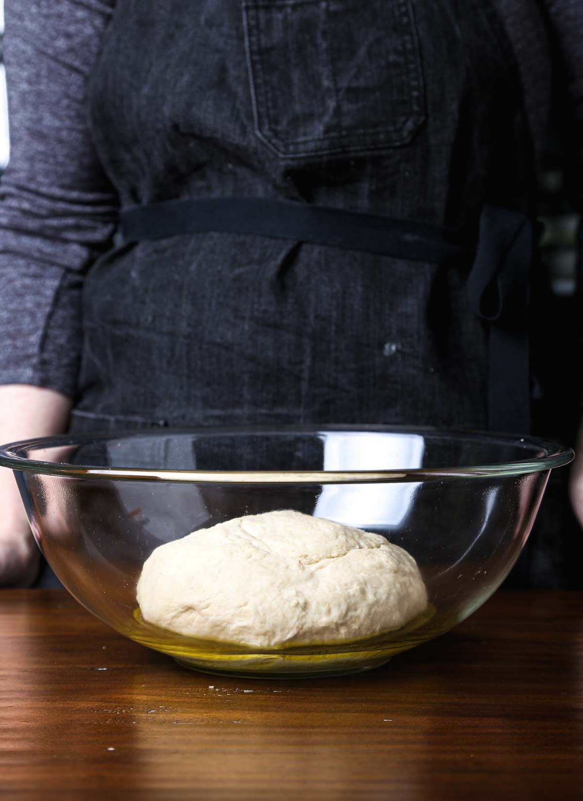 Ball of bread dough resting in a glass bowl lightly coated with oil before rising.