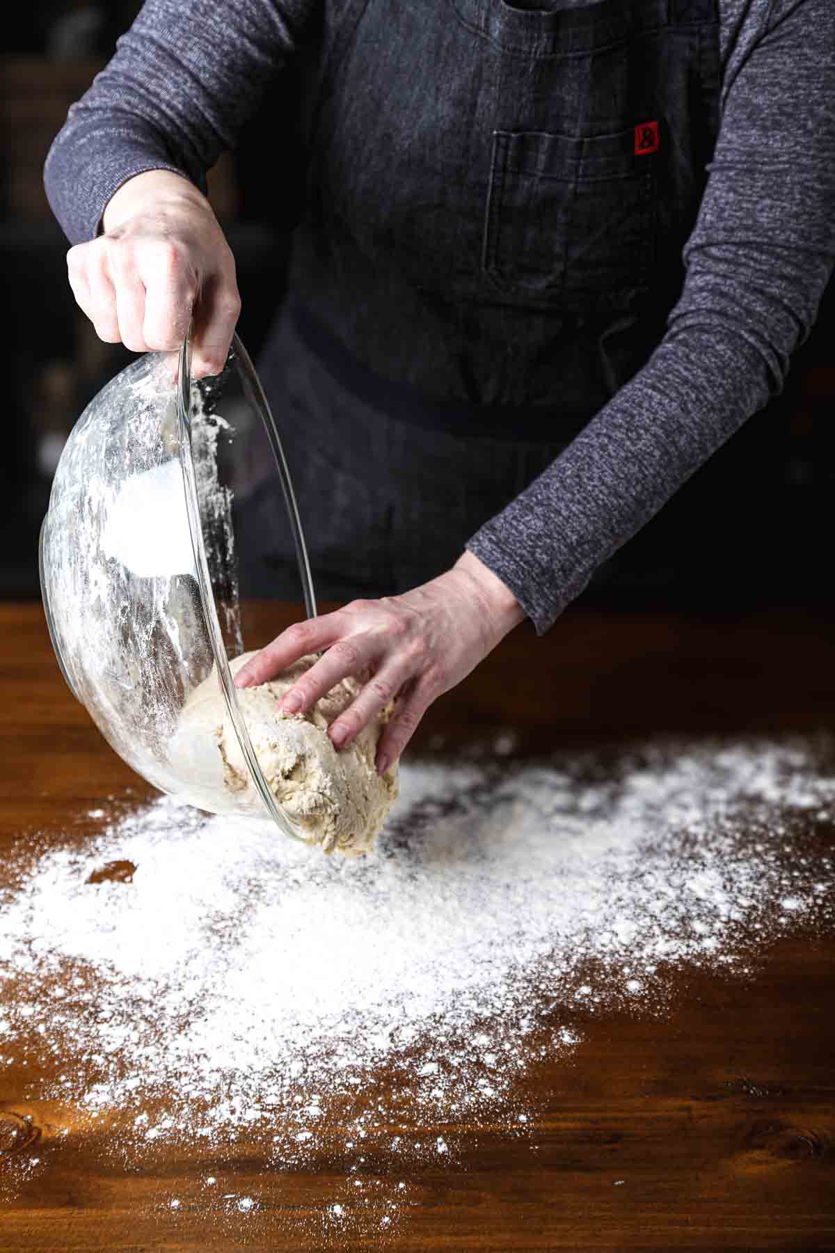 Transferring the mixed bread dough from the bowl onto a floured surface.