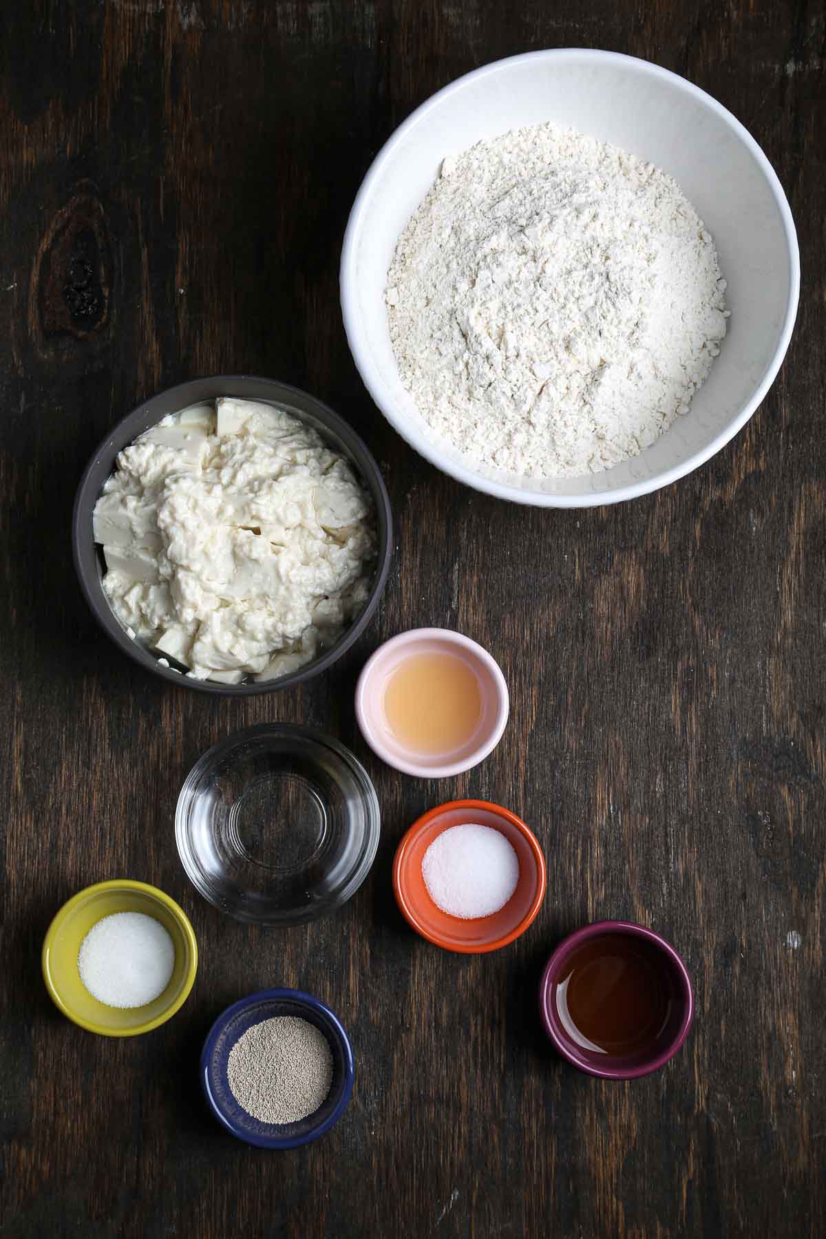 Ingredients for the sandwich bread laid out in bowls, including bread flour, silken tofu, yeast, salt, vinegar, water, and oil.