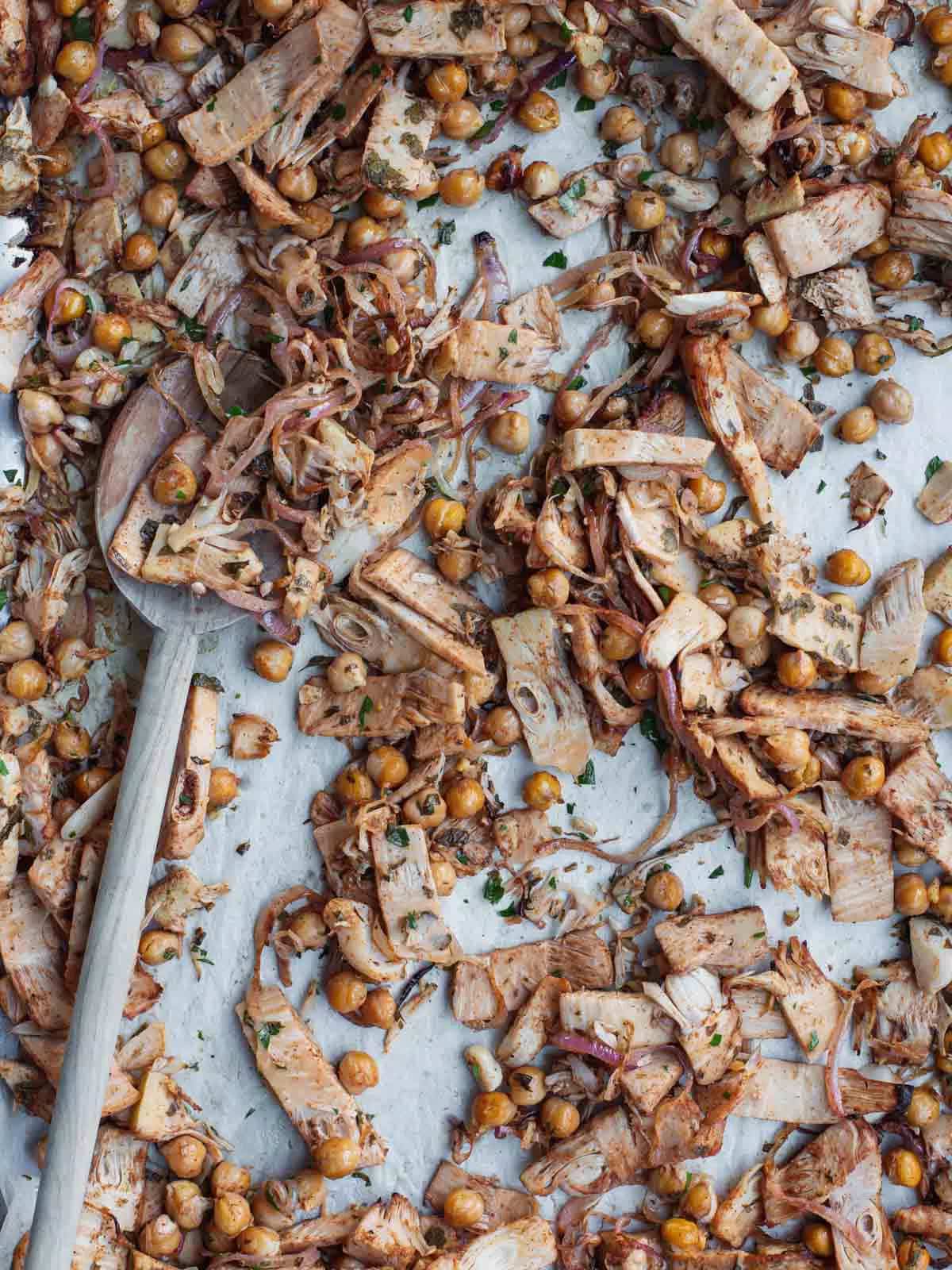 Roasted jackfruit shawarma with chickpeas, onions, and spices on a baking sheet.