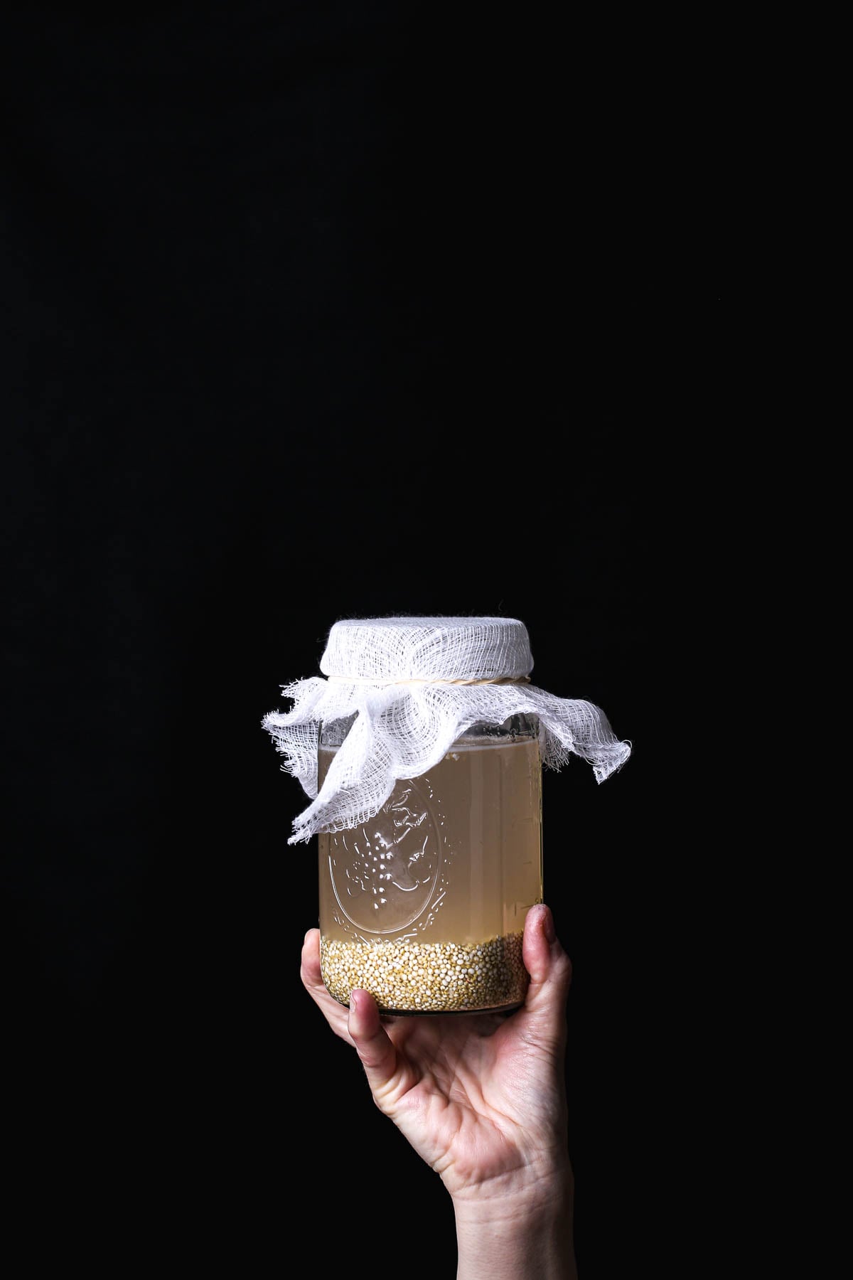 Quinoa soaking in water in a glass jar to begin the rejuvelac sprouting process.