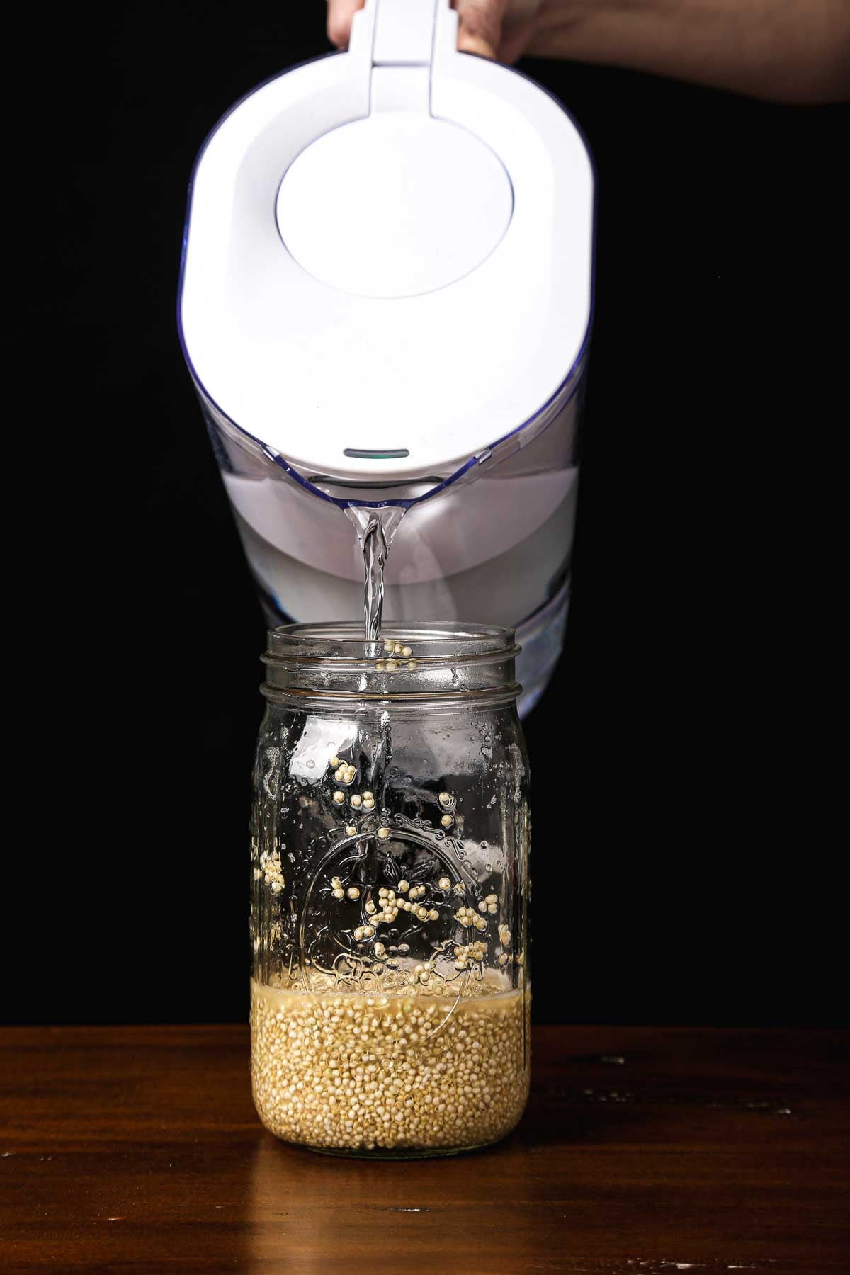 Adding water to a jar of quinoa during the sprouting stage.