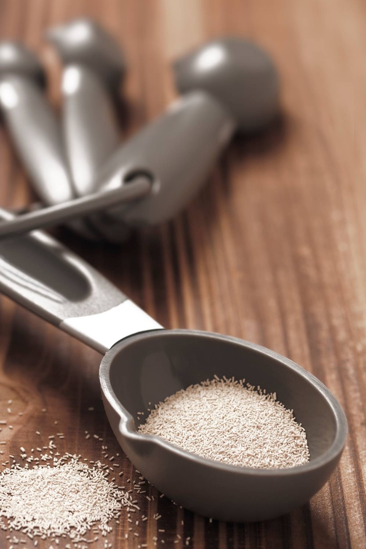 Active dry yeast granules in a measuring spoon, shown before proofing to test if the yeast is still good.