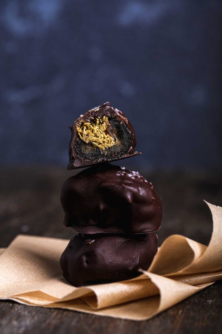 Cross-section of a chocolate-covered date revealing crisp kataifi and pistachio filling inside a soft Medjool date.