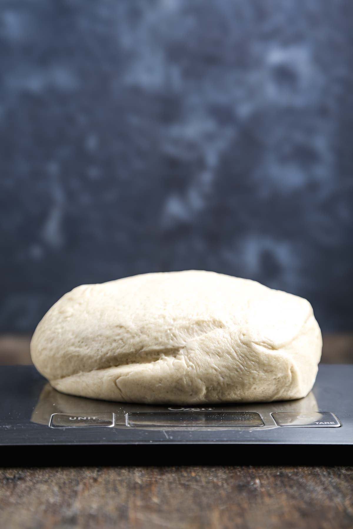 Portioned pizza dough being weighed on a digital kitchen scale before shaping.
